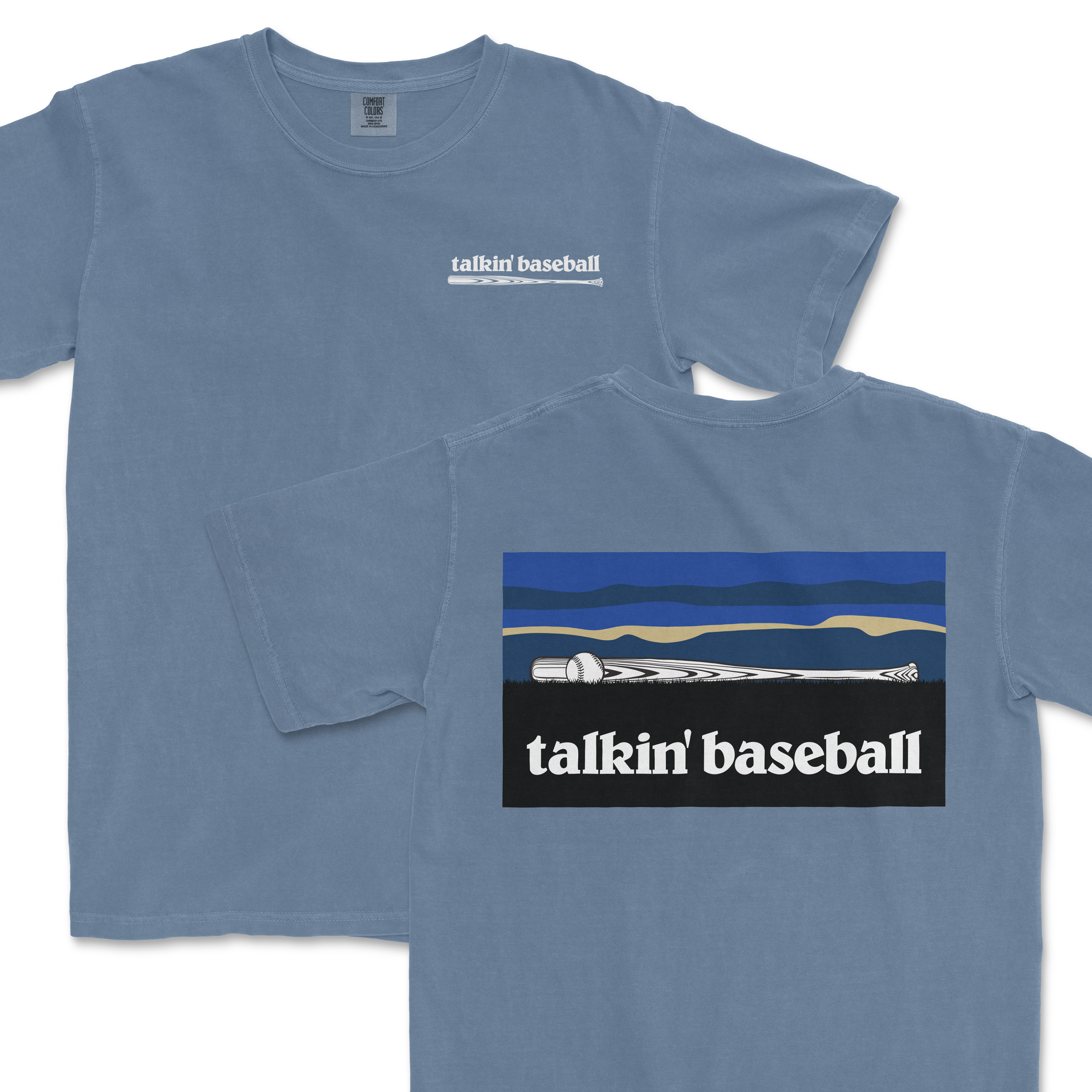 Light blue T-shirt featuring a small "talkin' baseball" logo with a baseball bat and ball on the front, and a larger graphic of a baseball bat and ball against a stylized landscape on the back.