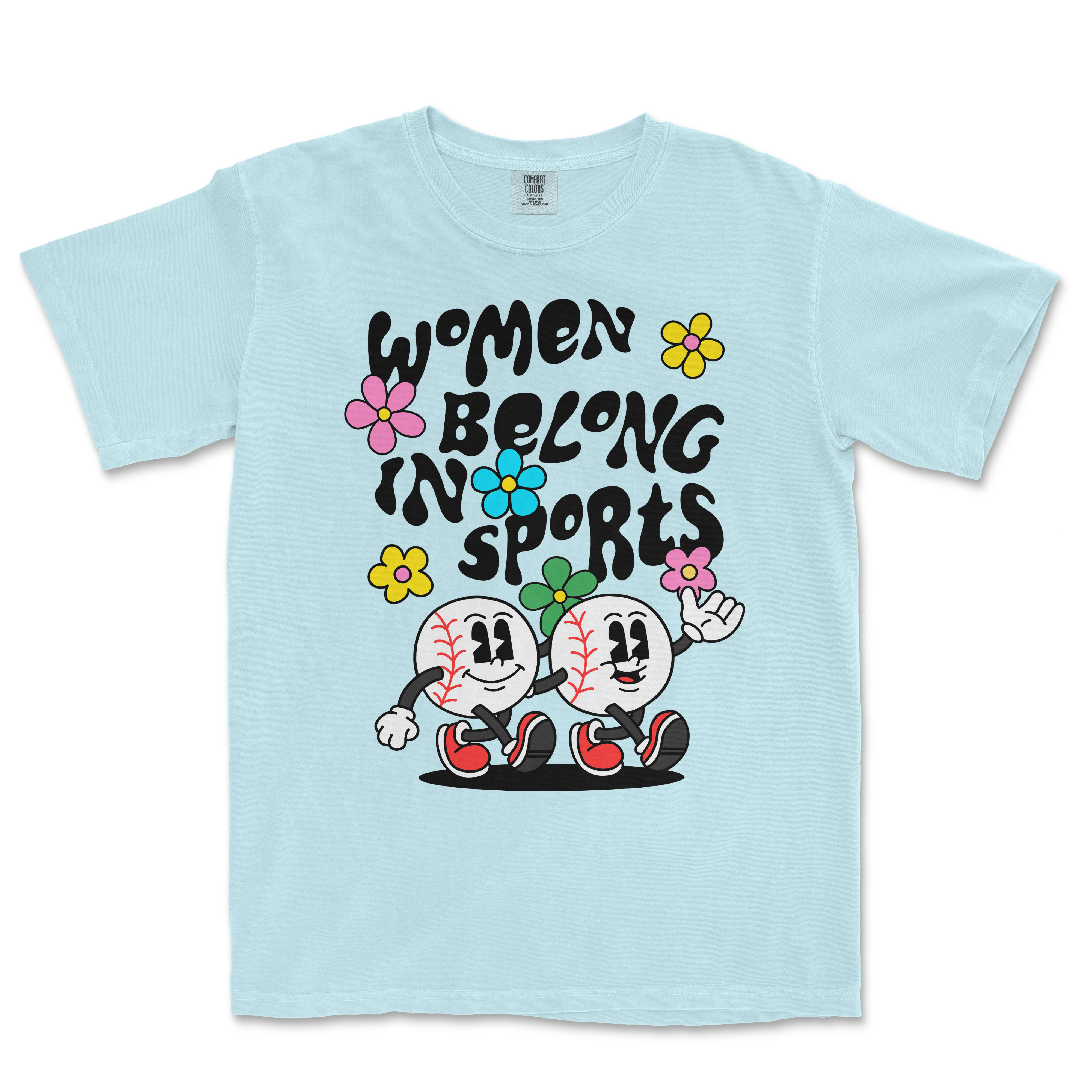 Light blue T-shirt featuring cartoon baseball characters, colorful flowers, and the text "Women Belong in Sports" in bold black letters.