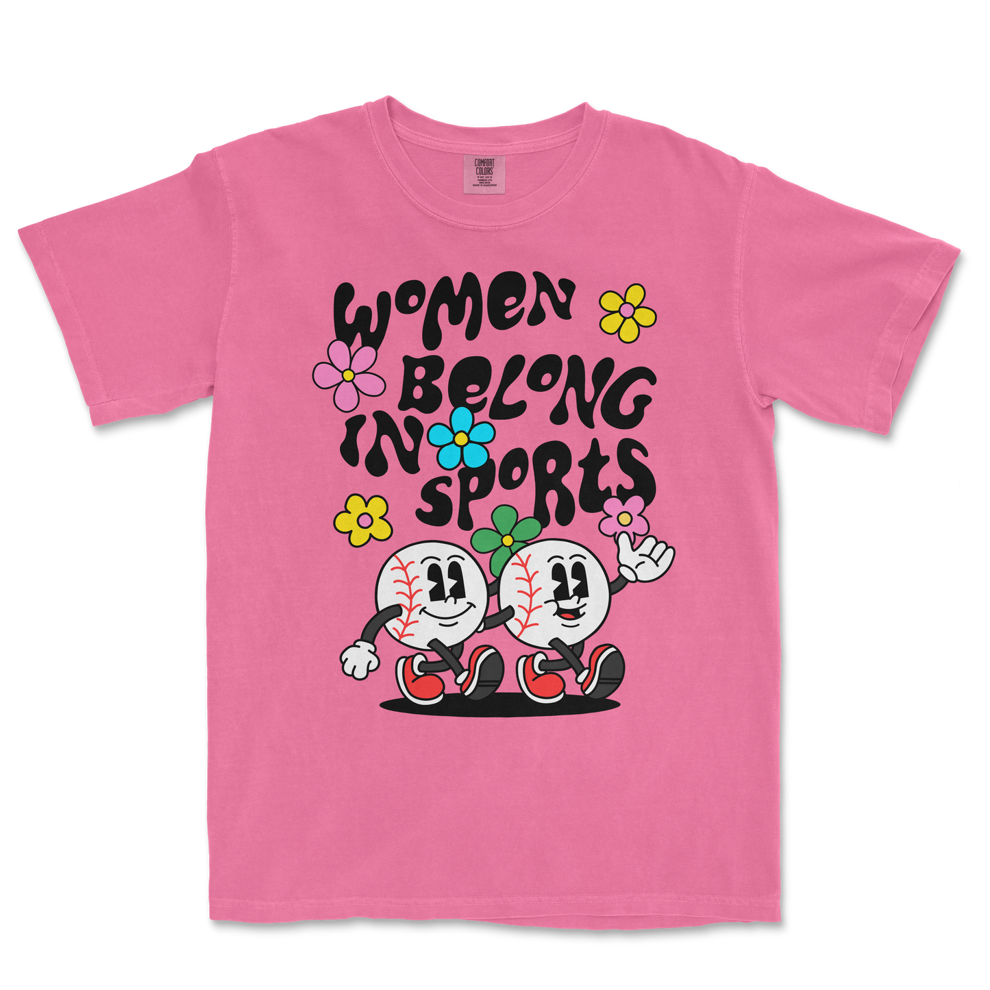 Pink T-shirt with cartoon baseball characters, colorful flowers, and the text "Women Belong in Sports" in bold black letters.