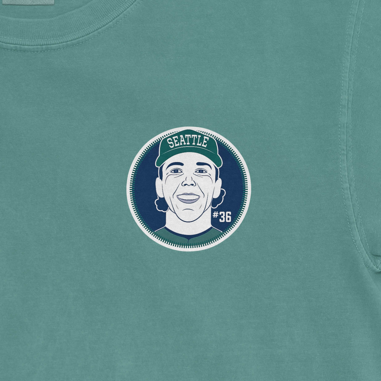 Close-up of a Comfort Colors tee featuring a graphic of a woman wearing a Seattle cap, with the number 36 on the shirt.