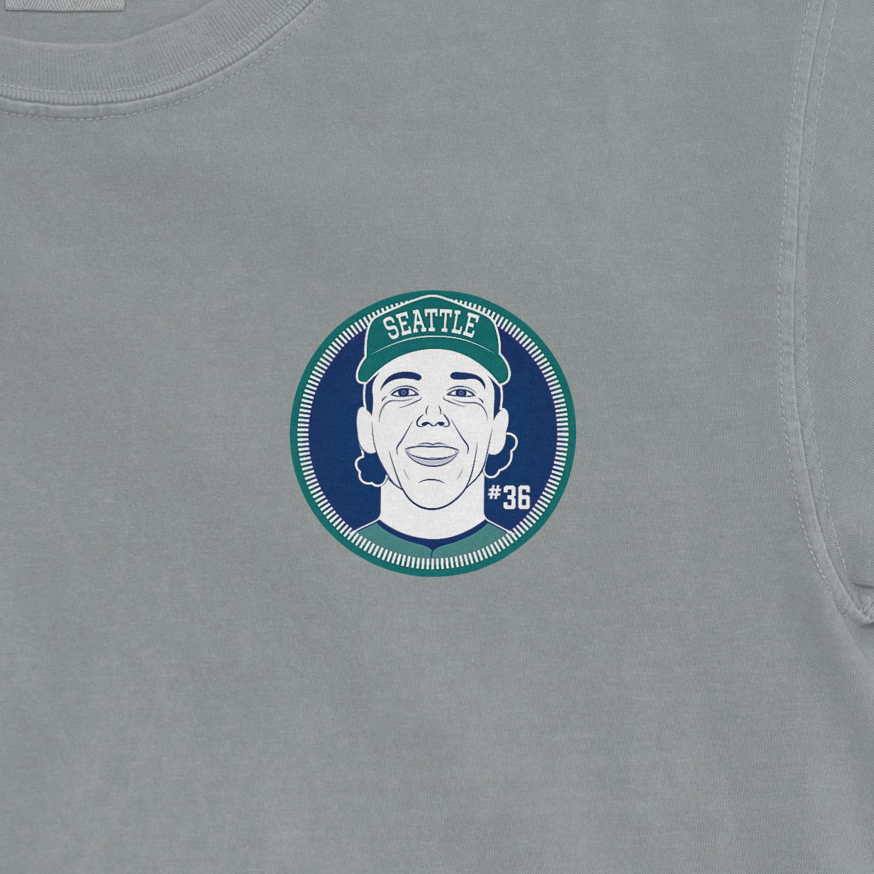 Close-up of a Comfort Colors tee featuring a graphic of a woman wearing a Seattle cap, with the number 36 on the shirt.