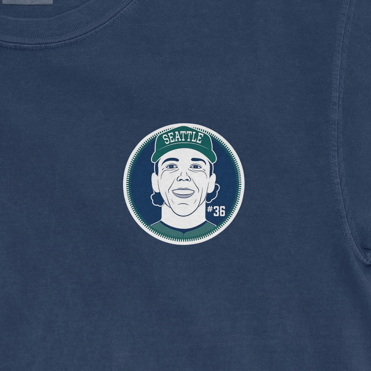 Close-up of a Comfort Colors tee featuring a graphic of a woman wearing a Seattle cap, with "#36" on a dark blue background.