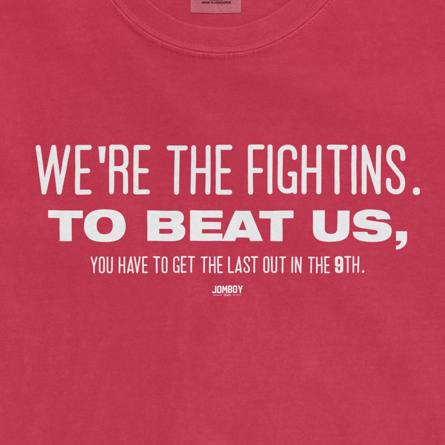 Pink T-shirt with white text reading "We're the Fightins. To beat us, you have to get the last out in the 9th." and "Jomboy" logo.