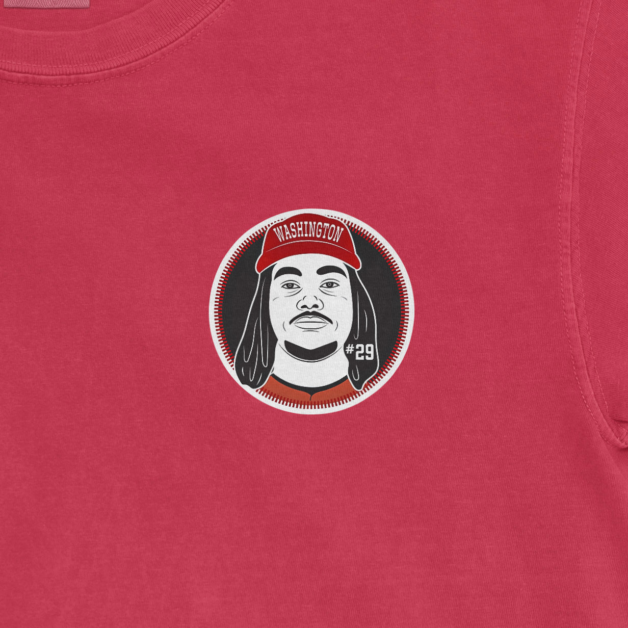 Close-up of a red Comfort Colors tee featuring a graphic of a person with dreadlocks, wearing a red Washington hat, and "#29" on the shirt.