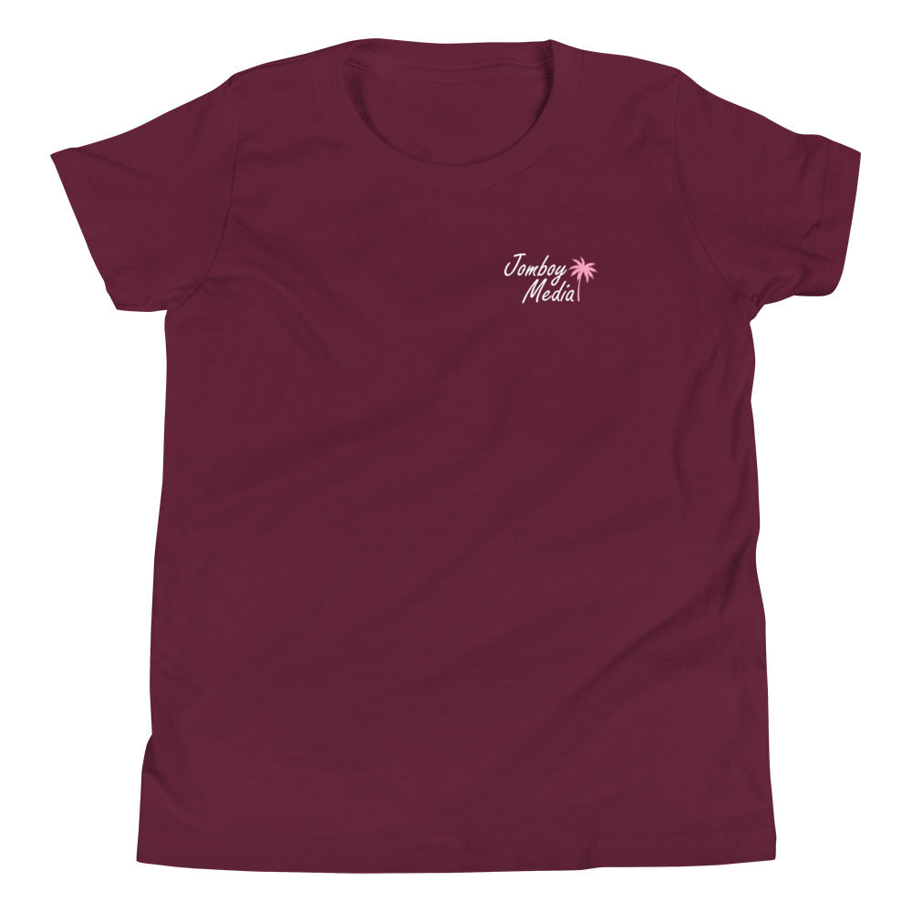 Maroon youth T-shirt with "Greetings from Jomboy Media" text and pink palm tree graphic on the chest.