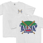 White Comfort Colors tee featuring a graphic design with crossed baseball bats and the text "Talkin' Baseball" in stylized lettering, with a green and purple background. The upper left corner includes a simple crest with the initials "TXB".