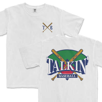 White Comfort Colors tee featuring a graphic design with crossed baseball bats and the text "Talkin' Baseball" in stylized lettering, with a green and purple background. The upper left corner includes a simple crest with the initials "TXB".