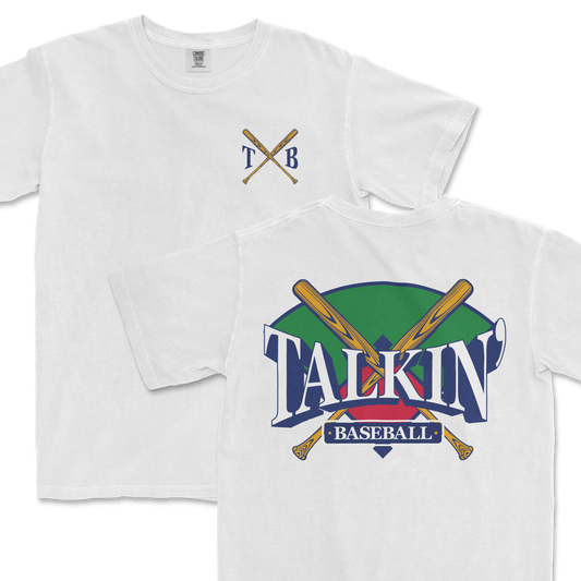 White Comfort Colors tee featuring a graphic design with crossed baseball bats and the text "Talkin' Baseball" in stylized lettering, with a green and purple background. The upper left corner includes a simple crest with the initials "TXB".