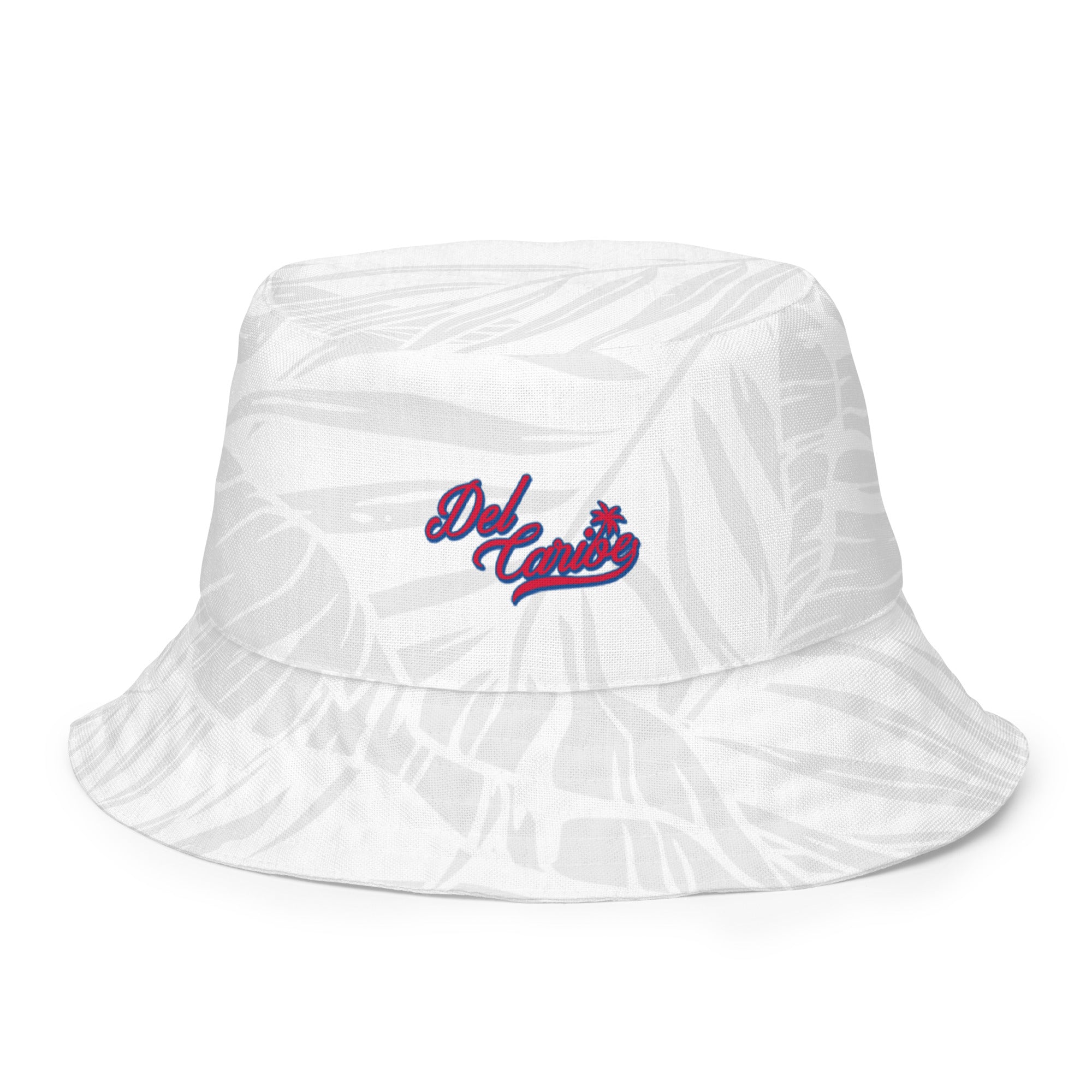 White reversible bucket hat with a subtle leaf pattern and "Del Caribe" embroidered in red and blue on the front.