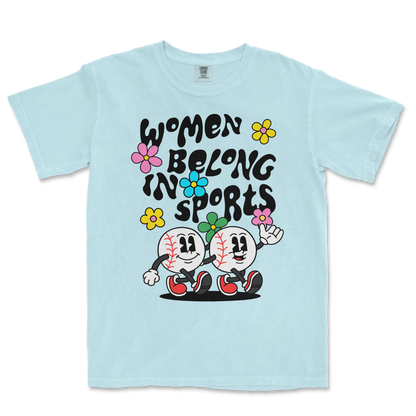 Light blue T-shirt featuring cartoon baseball characters, colorful flowers, and the text "Women Belong in Sports" in bold black letters.