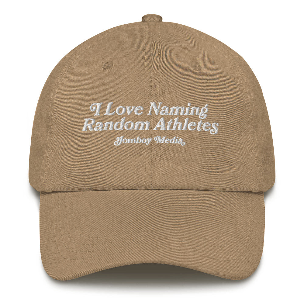 Beige dad hat with white embroidered text: "I Love Naming Random Athletes" and "Jombay Media" underneath.