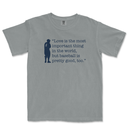 Gray Comfort Colors T-shirt featuring a navy silhouette of a baseball player and the quote: "Love is the most important thing in the world, but baseball is pretty good, too.