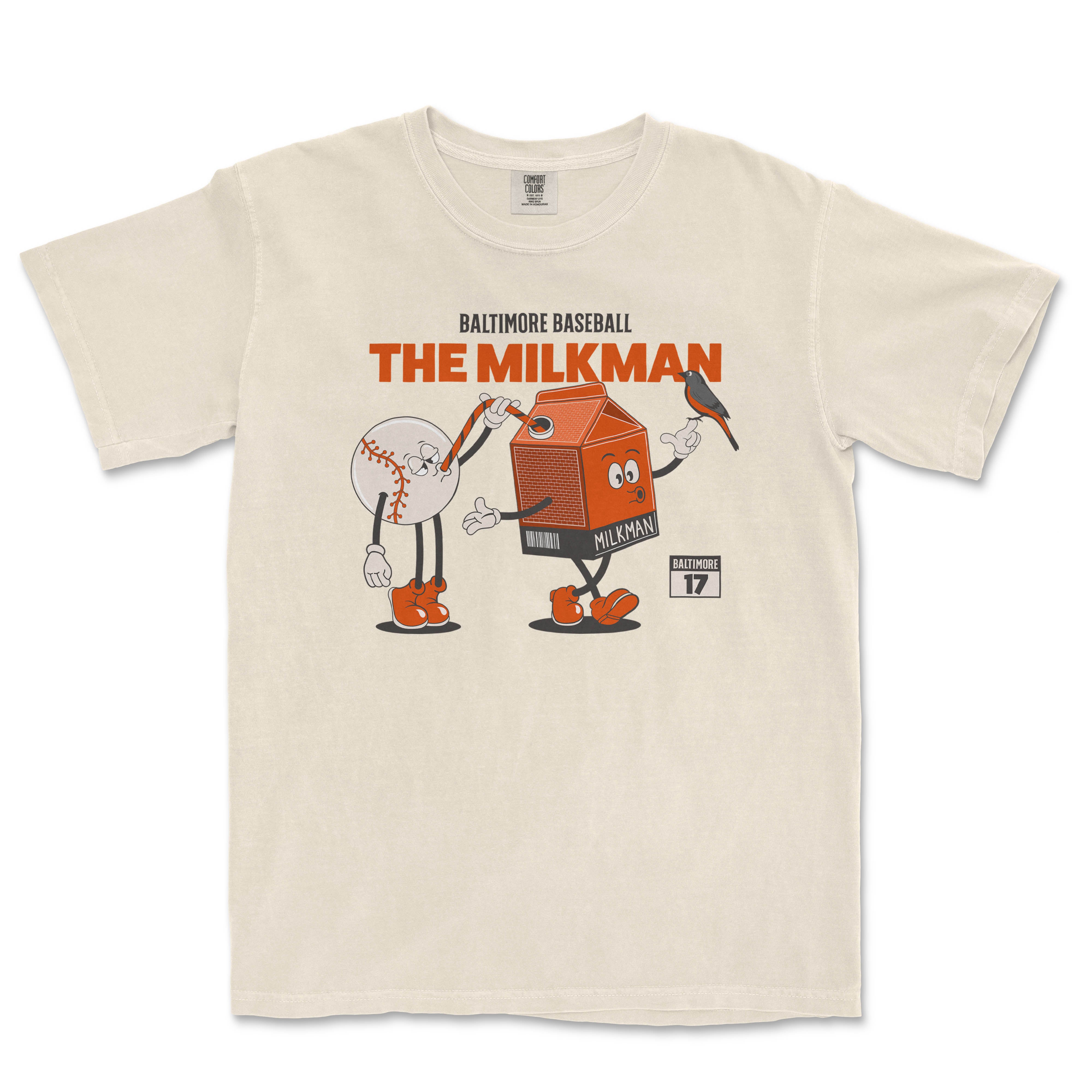 Beige T-shirt featuring cartoon characters of a baseball and a milk carton, with "The Milkman" and "Baltimore 17" text.