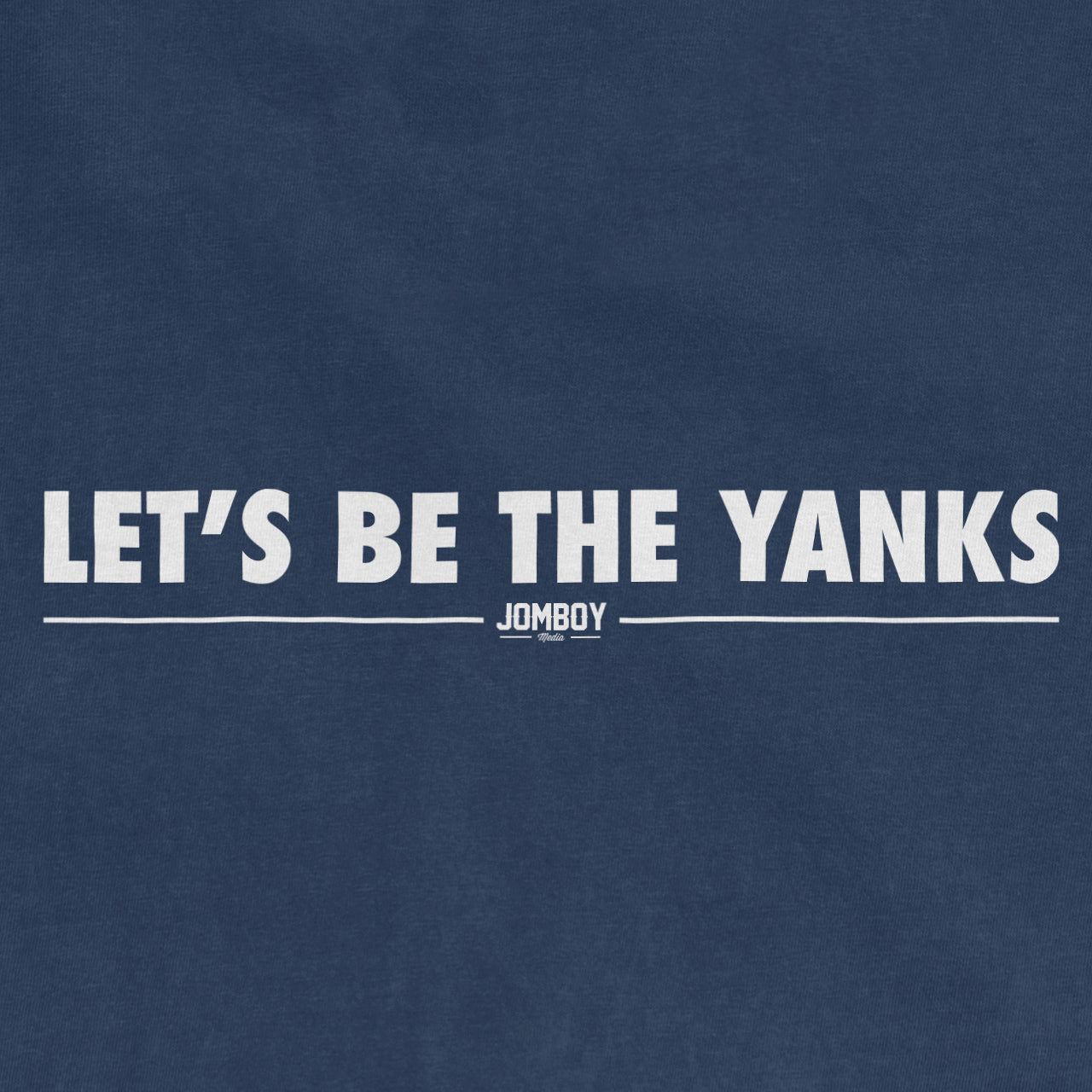 Close-up of a blue fabric with white text reading "LET'S BE THE YANKS" and a small "JOMBOY" logo below.